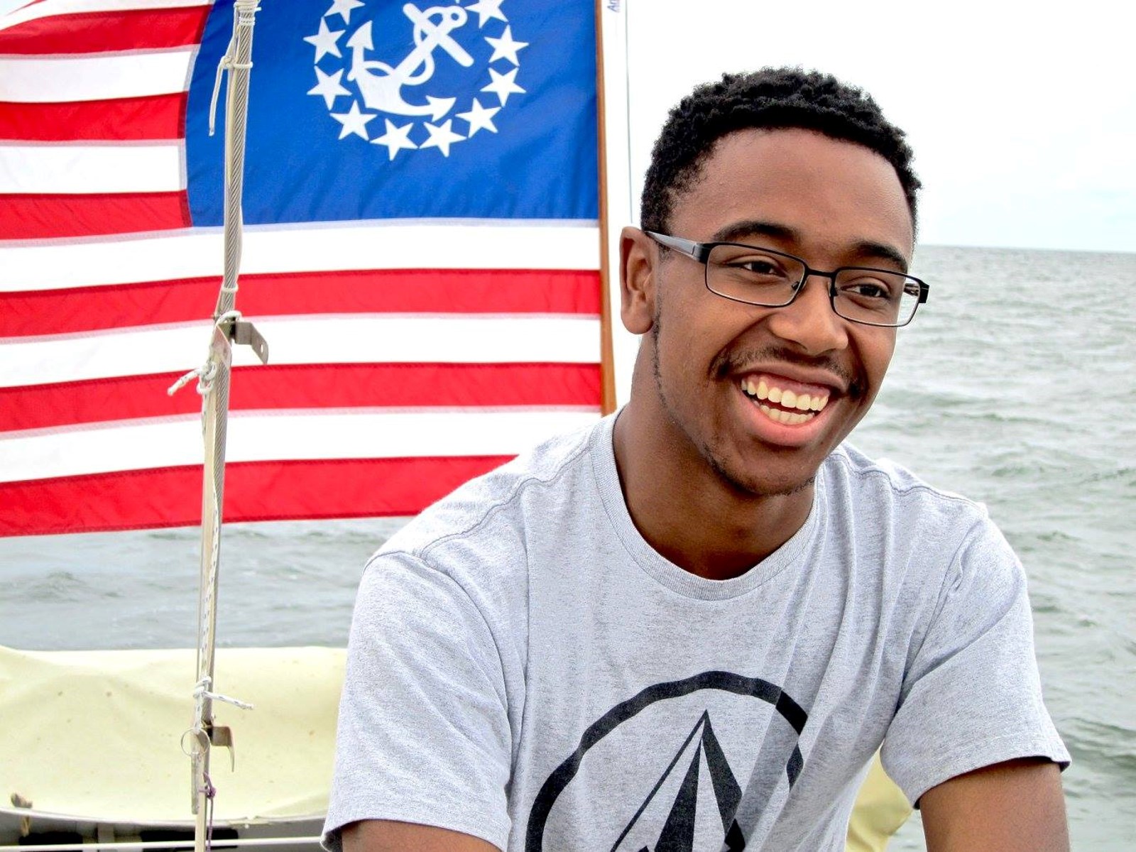 Aaron smiling with his countries flag behind him