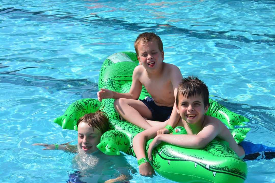 Three Slack boys enjoy playing a large green pool float together