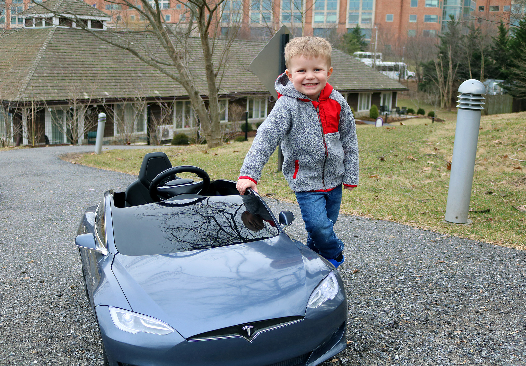 Carson standing next to his child size Tesla