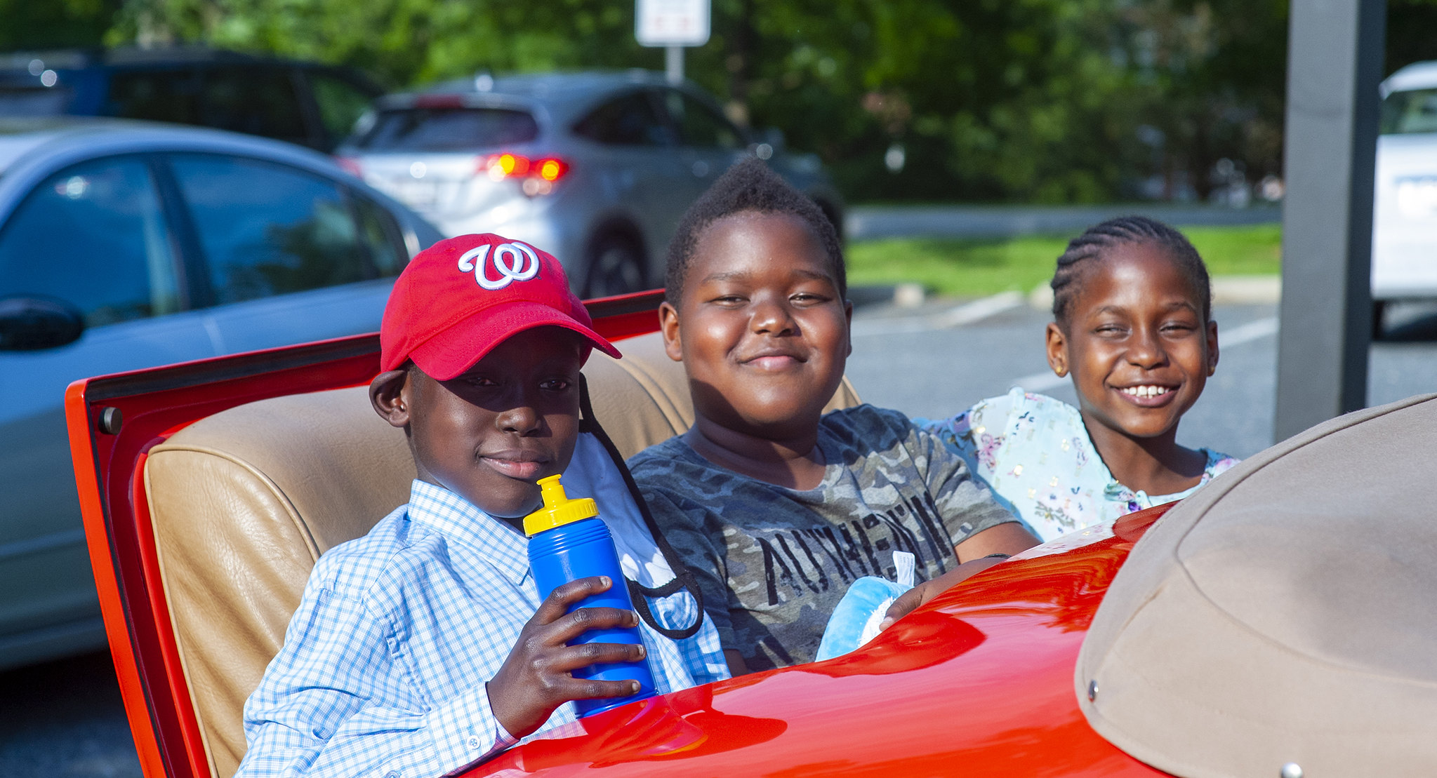 Three kids have fun outside at the car show